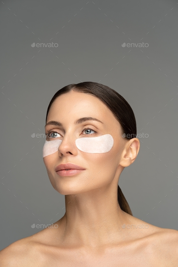 Woman applying hydrogel undereye recovery patches with collagen
