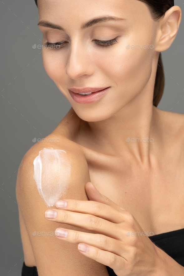 Woman applying sunscreen cream or cosmetic moisturizing lotion on