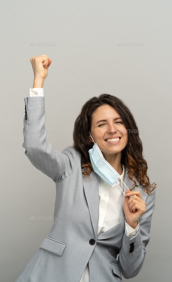 Studio portrait of happy business woman taking off mask from face