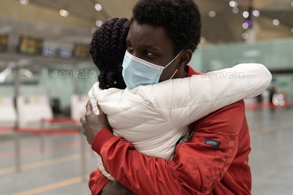 African couple wear face masks hugging each other within the new normality at airport terminal