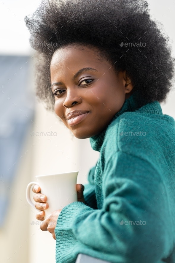 African American biracial woman enjoying a cup of tea or coffee, wear oversize green knitted sweater