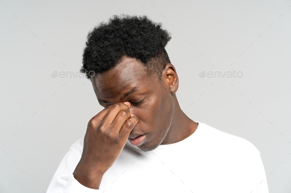 Exhausted black male wants to sleep, rubbing his eyes, feels tired after work on laptop. Overwork.