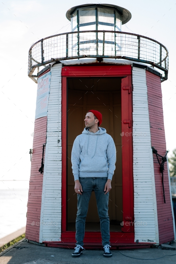 Man tourist at lighthouse building. Millennial traveler one pose at light house. Lifestyle concept