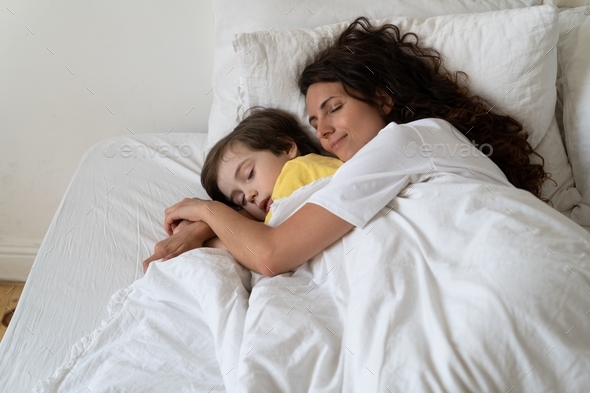 Peaceful loving mum hug preschool son sleeping together with child in ...