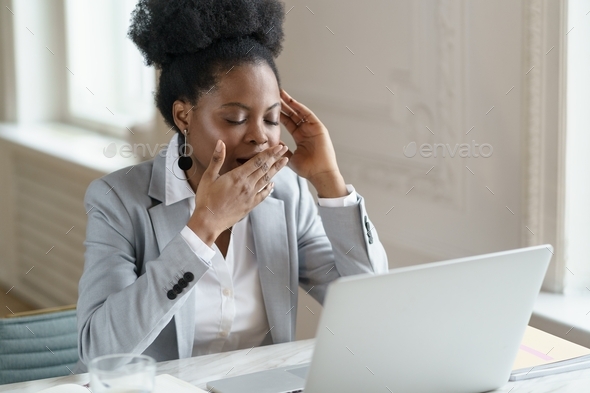 Tired Afro office employee in blazer yawn in workplace, suffering from ...