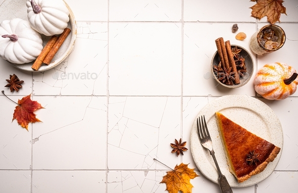 Piece of american pumpkin pie with cinnamon on white tile background ...