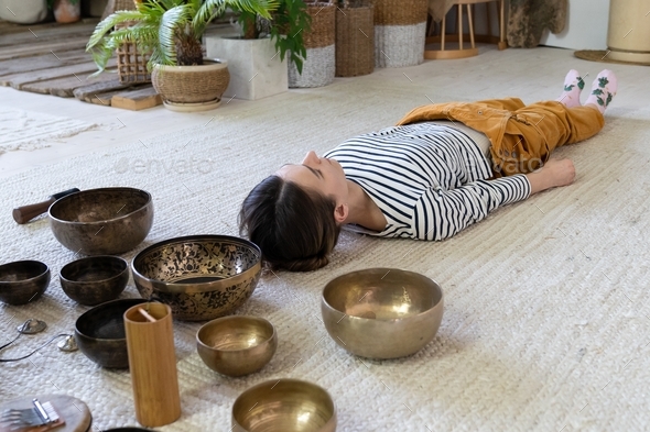 Girl meditate with singing bowls during tibet massage and sound therapy. Tibetan spiritual practices