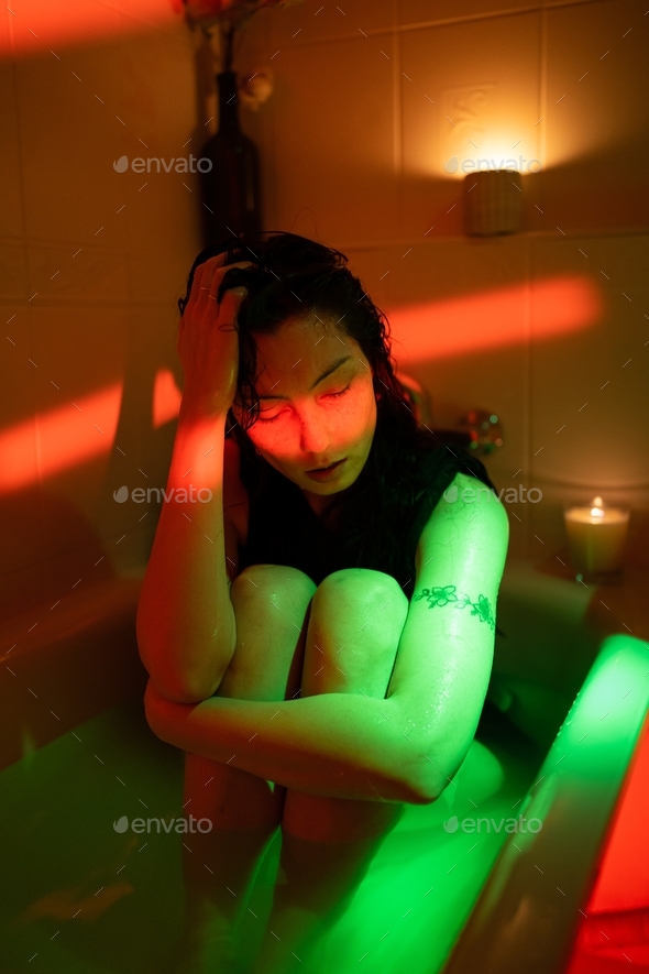 Depressed asian woman sit in bath with cold water think of love problem, break up or ruined marriage
