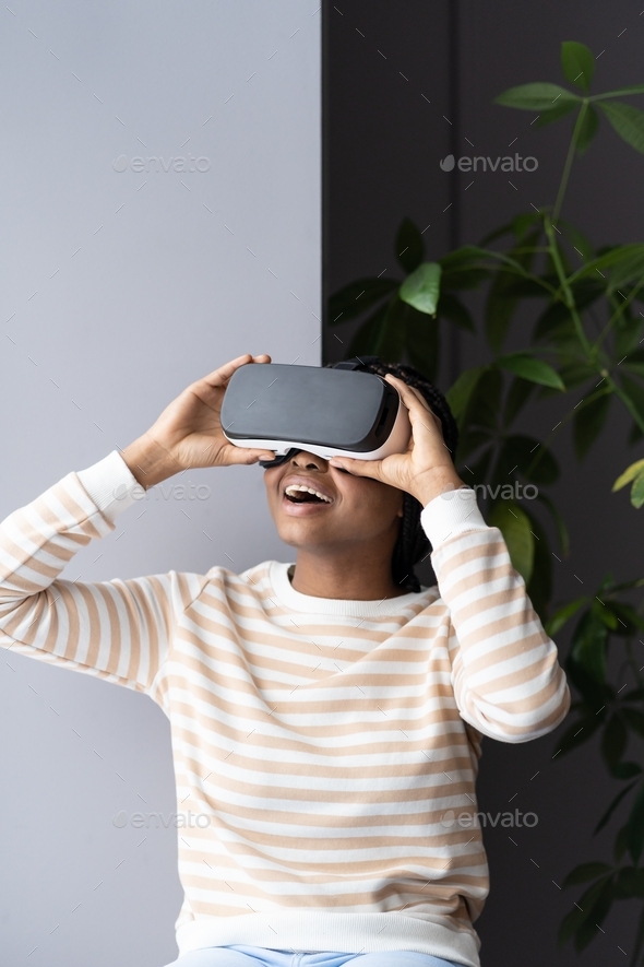 Afro woman play on vr glasses. Virtual reality and wearable tech. Female has fun wearing headset