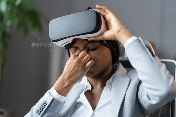 Young african american business woman suffering from eye strain after using VR headset at workplace