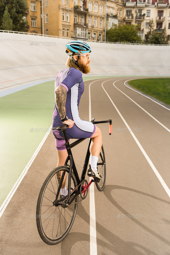 back view of cyclist in sportswear and helmet with bicycle on