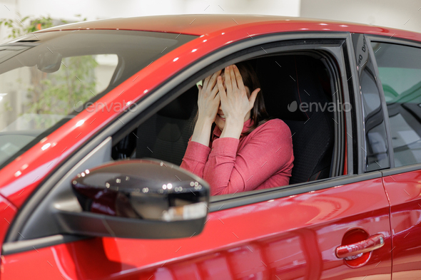happy woman buys a red car at a car dealership. signing a trade-in contract and handing over keys