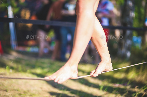 A young woman is walking on a tightrope. Legs close up. A tightrope walker.