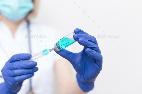 Vaccine covid 19. Gloved hands hold the vaccine. The doctor draws the vaccine into a syringe.