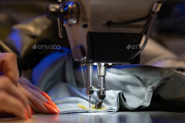 Closeup of female seamstress, tailor or designer sew on sewing machine. Sewing industry production