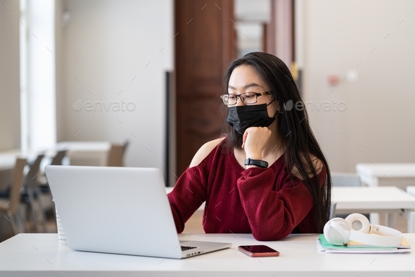 Asian girl wear medical mask at university class studying on laptop in covid-19 disease pandemic