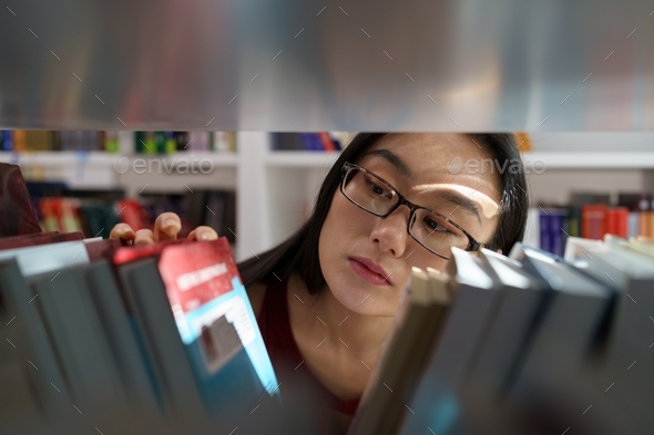 Young asian college girl searching for academic journals, books and primary sources in library