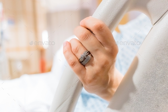 Mother in labor holding on to the hospital bed rail, birth
