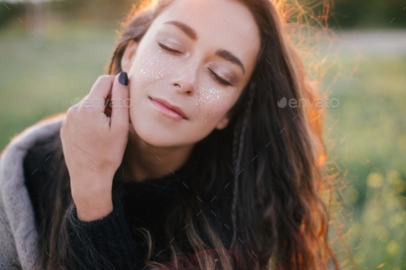 Young woman with shiny temporary tattoos on face close up portrait