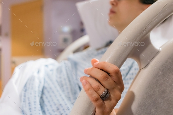 Pregnant woman in hospital bed holding on to bed rail during contractions