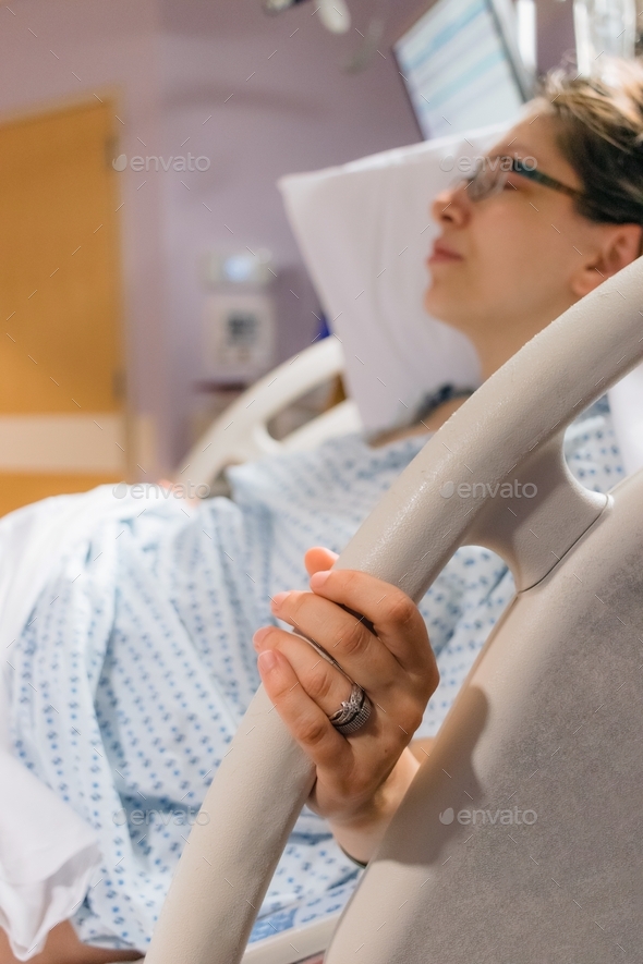 Pregnant mother in hospital bed about the give birth holding on the rails during contractions