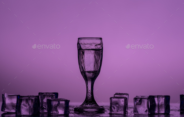 Purple monochrome image of a shot glass and ice cubes on the table  - Stock Photo - Images