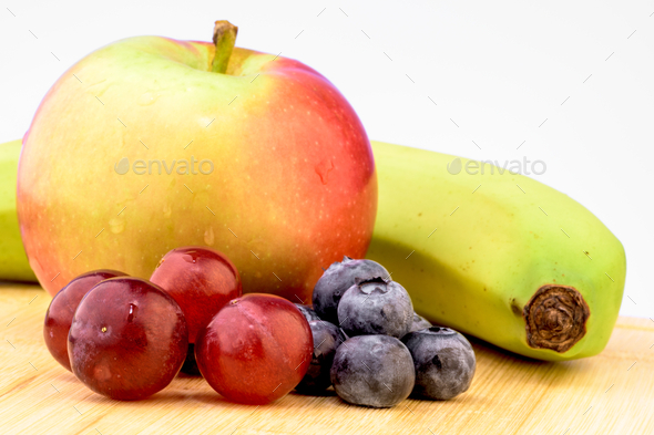 Healthy eating, healthy fruits on a cutting board against white background; banana, grapes, apple - Stock Photo - Images