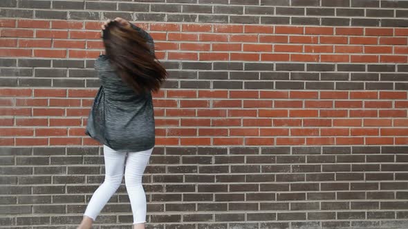 Young Woman Dancing Against a Brick Wall Walking Around the City alt