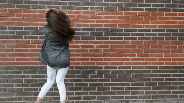 Young Woman Dancing Against a Brick Wall Walking Around the City
