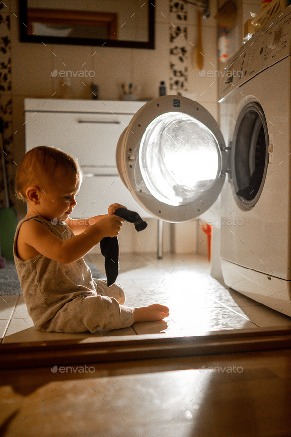 The baby in the bathroom is looking at the washing machine Stock Photo ...