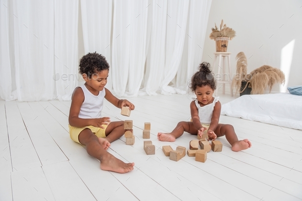 Little Brother and Sister African American play houses with wooden eco bricks, build destroy towers
