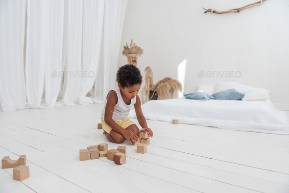 Little happy boy African American play houses with wooden eco br