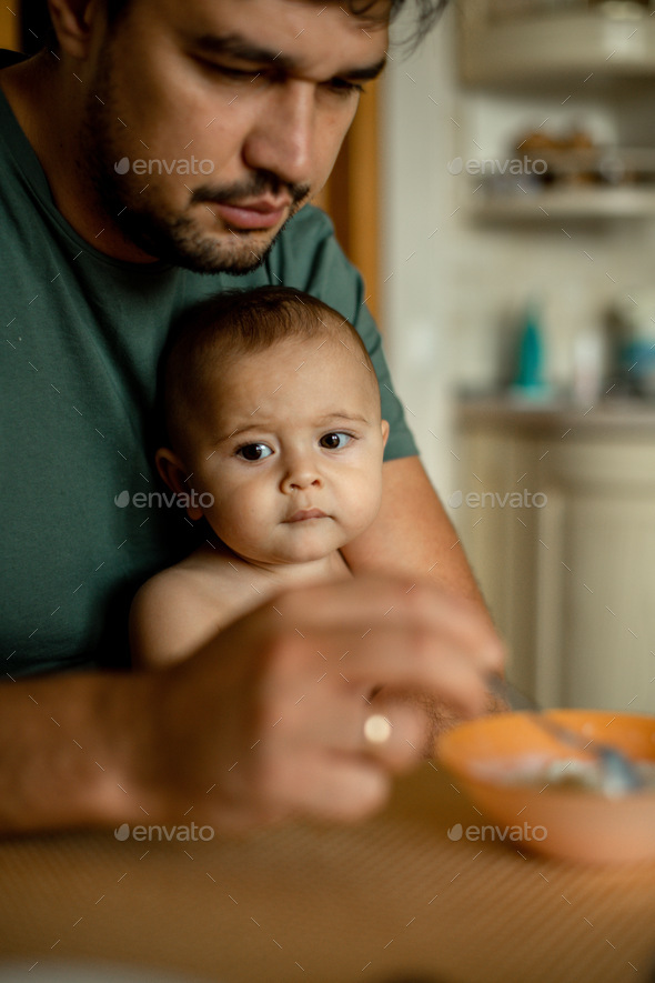 Dad feeds his son porridge. The family has breakfast Stock Photo by