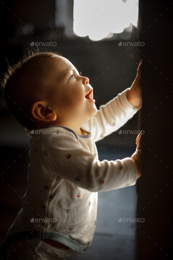 Portrait of a baby. Dark key. A child in the rays of light - Stock Photo - Images