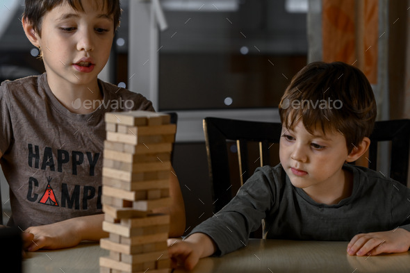 The boys are playing Jeng's game. The brothers are building a tower of wooden sticks - Stock Photo - Images