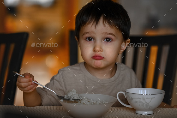 A little boy eats porridge for breakfast - Stock Photo - Images