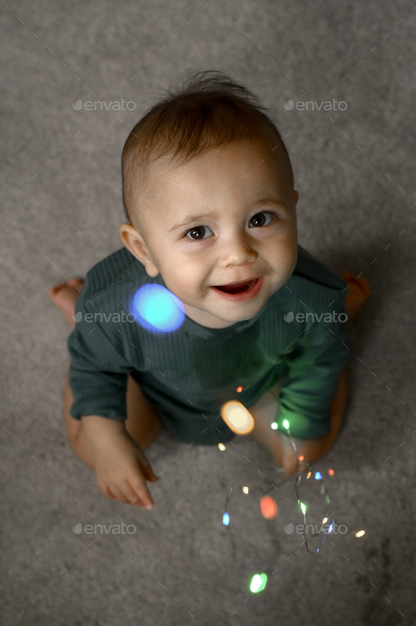 Portrait of a one-year-old baby, the child plays with a glowing garland - Stock Photo - Images