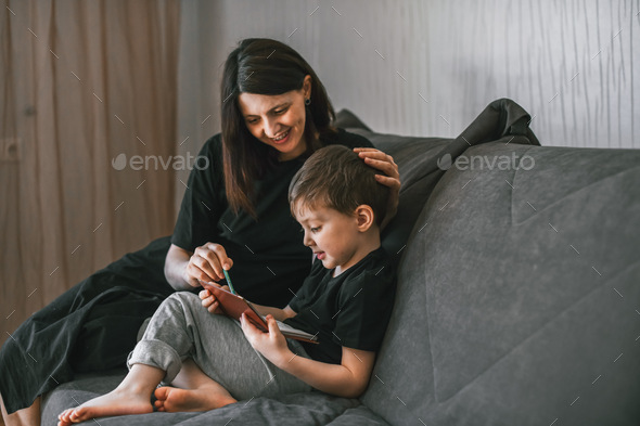 mom and son are sitting on the couch and drawing - Stock Photo - Images
