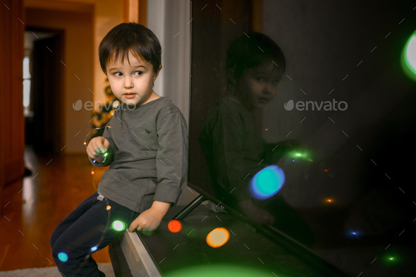 A three-year-old boy plays with a glowing garland - Stock Photo - Images