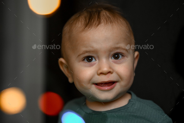 Portrait of a one-year-old baby, the child plays with a glowing garland - Stock Photo - Images