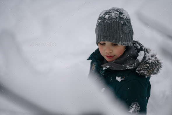 Portrait of a ten-year-old boy in winter in the park against the background of snow - Stock Photo - Images