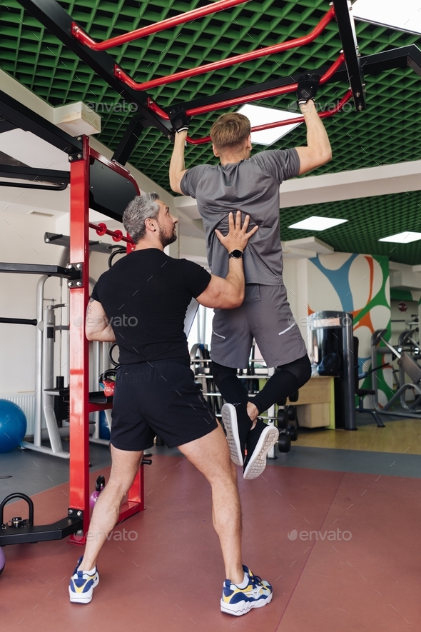 Personal sport coach training his client in the gym. sport and health routine. Support and guidance