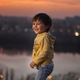 child at sunset on the river against the background of the city - PhotoDune Item for Sale