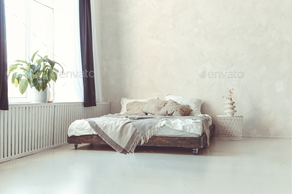 Stylish minimalist loft style bedroom interior with light concrete walls, king size wooden bed