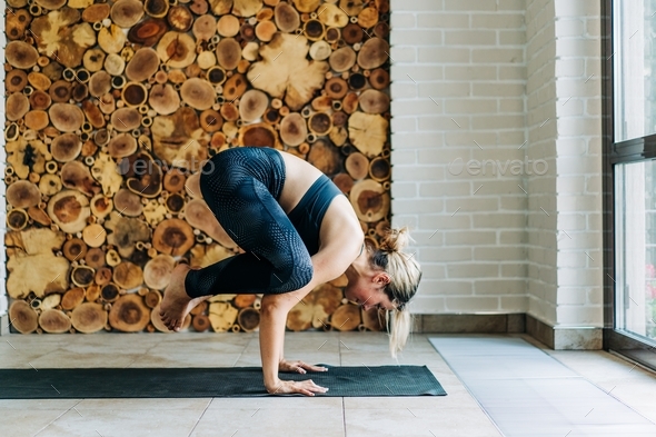 Strong vitality athletic woman doing yoga workout for balance at home.  Stock Photo by titovailona