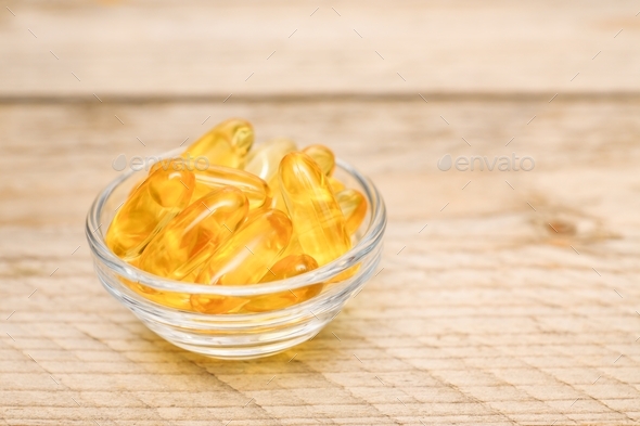Omega 3 gel capsules in glass bowl. Food supplements for healthy living