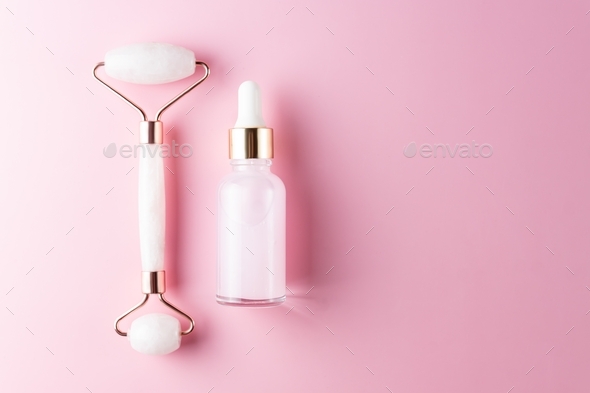 Massage quartz roller for the face of pink natural nephritis with beauty serum or essential oil.