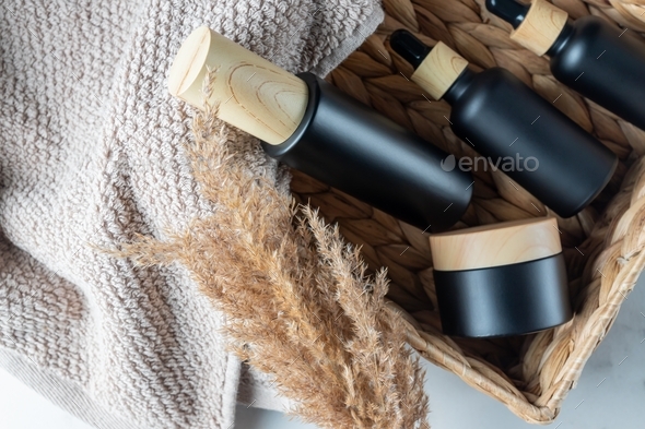 Facial and body care cosmetics bamboo bottles composition in eco basket with dry reeds grass.