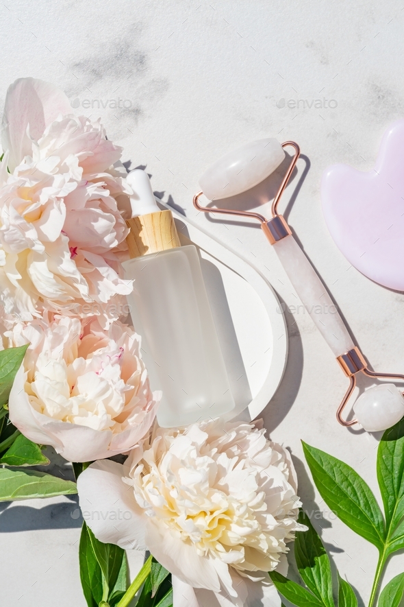 Pink Gua Sha facial massage tools. Rose Quartz jade roller and beauty facial oil on white marble