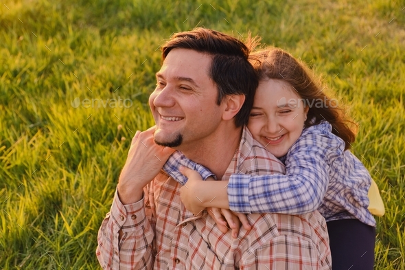 Smiling little girl hugging her father outside Stock Photo by InnaVlasova